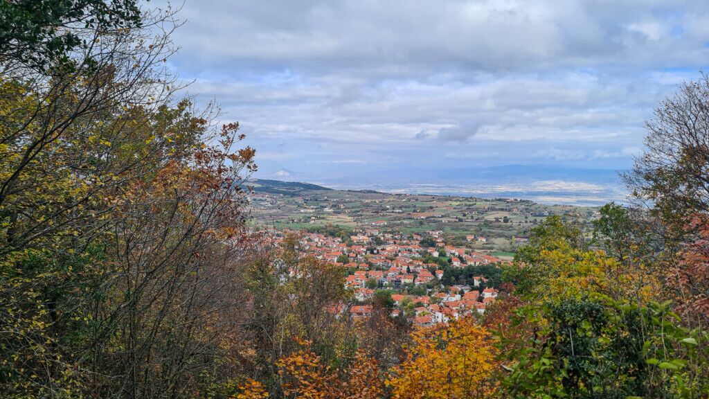 Halu! Scenic landscape view of Chortiatis nestled in a valley with lush trees in the foreground and a cloudy sky above offering a picturesque and serene atmosphere.